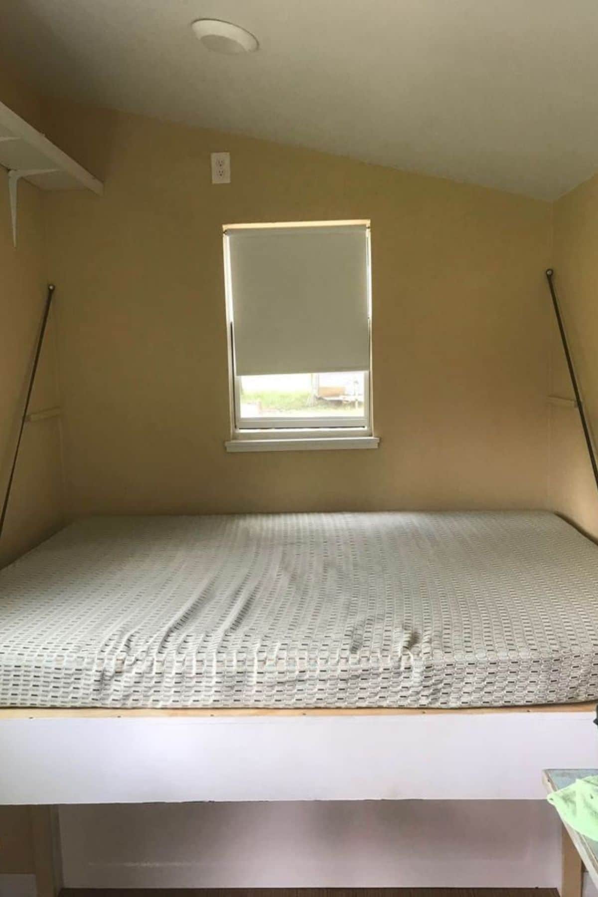 Murphy bed against cream wall with chain holding bed to wall