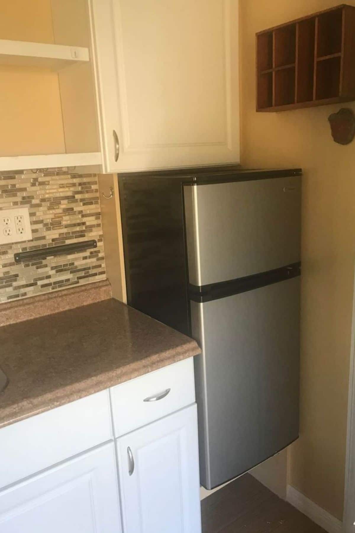 Small refrigerator next to kitchen cabinet