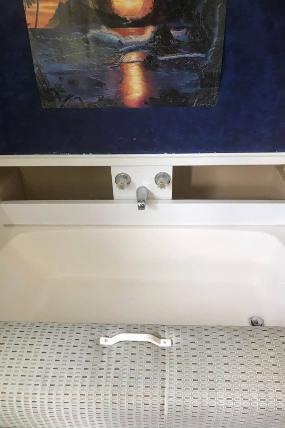 Bathtub with middle faucet under bench seat with blue painting above