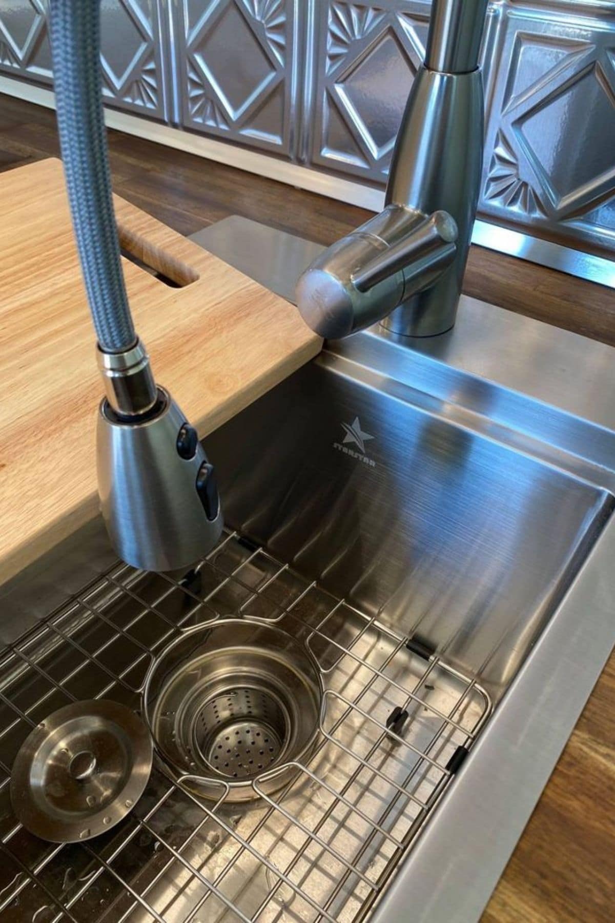 Dish drainer inside stainless steel sink with cutting board on top