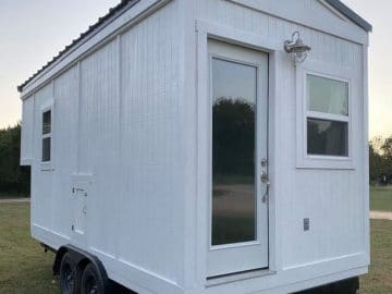 White tiny house on wheels with door at end