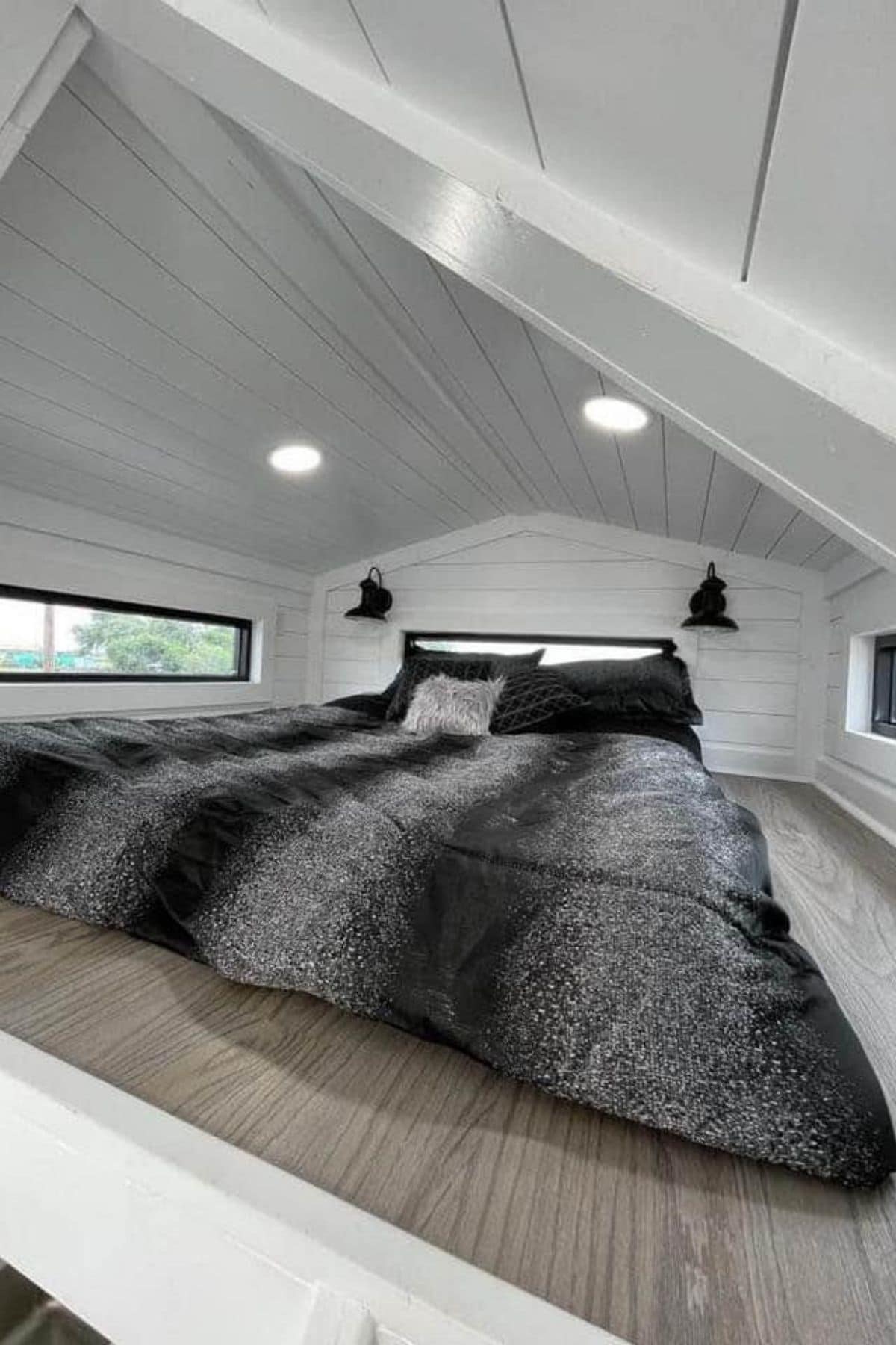 Black and gray bedding on mattress in white loft