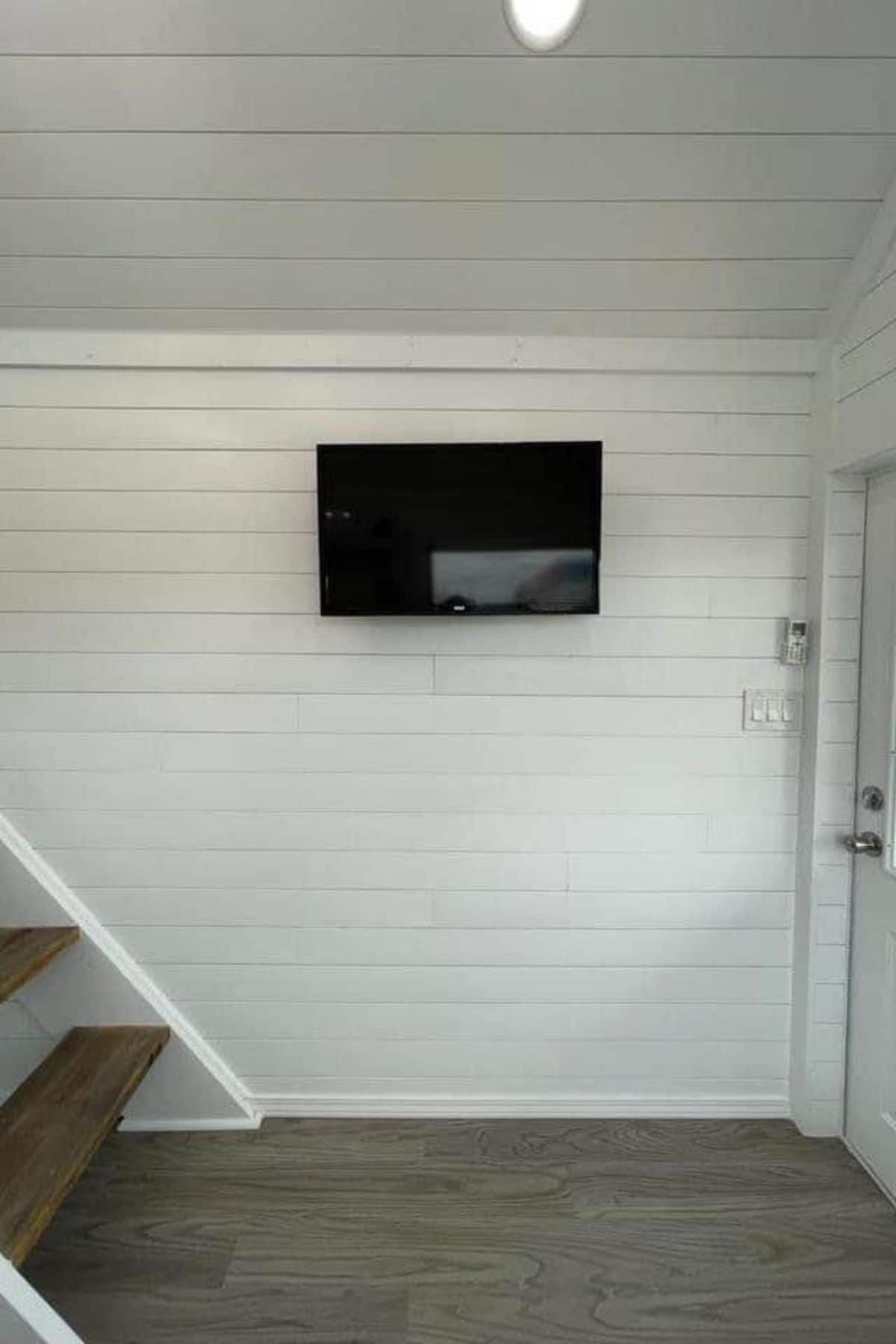 TV mountain on white shiplap wall by stairs to loft