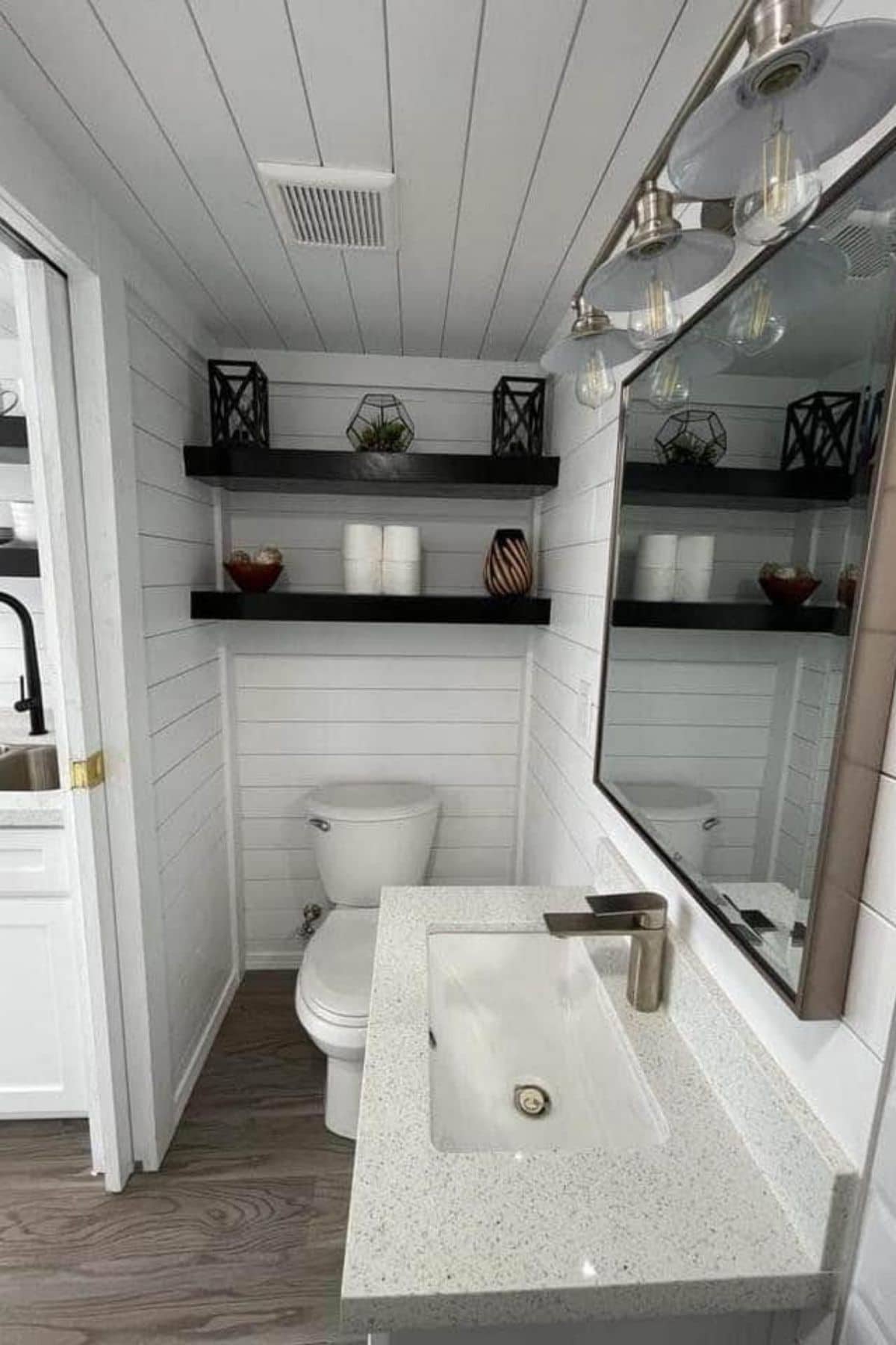 Floating shelves above toilet in tiny bathroom with white sink