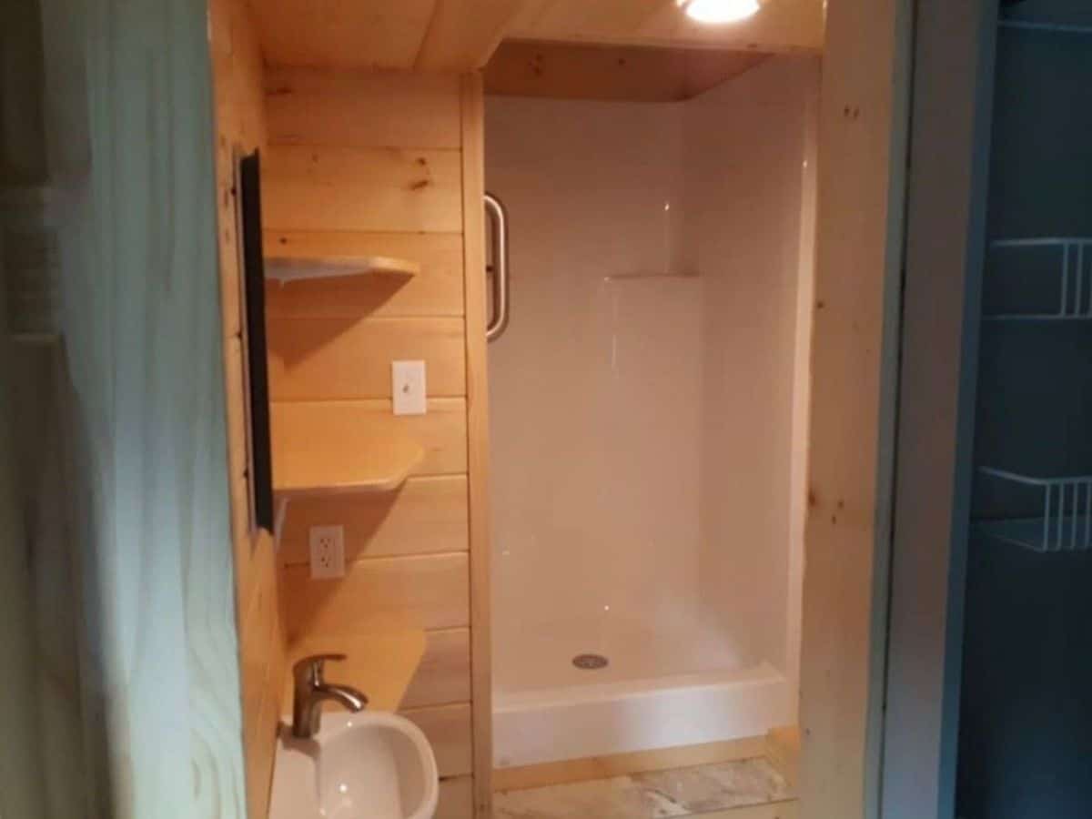 White shower stall in bathroom with light wood walls
