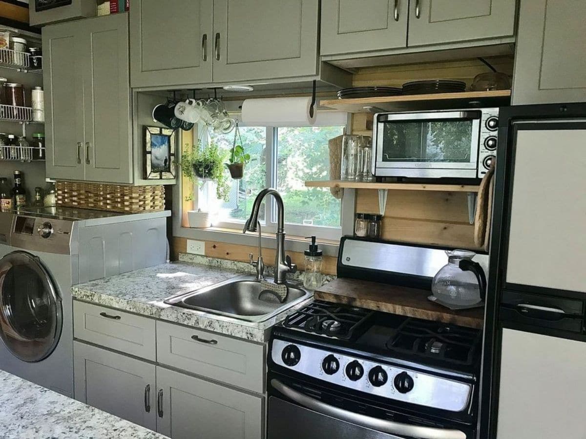 Full sized stove next to refrigerator and sink in tiny kitchen