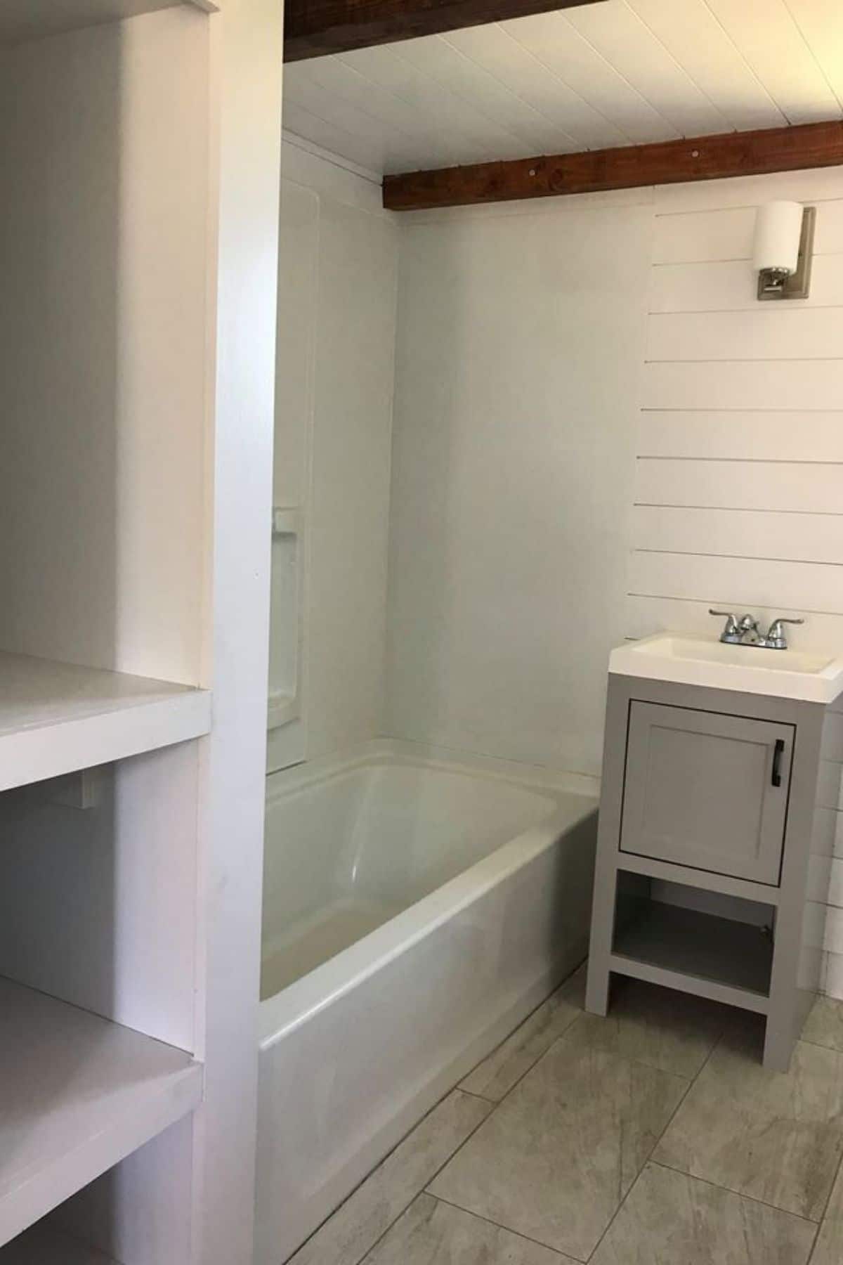 View into tiny house bathroom with shelves in foreground and bathtub in back