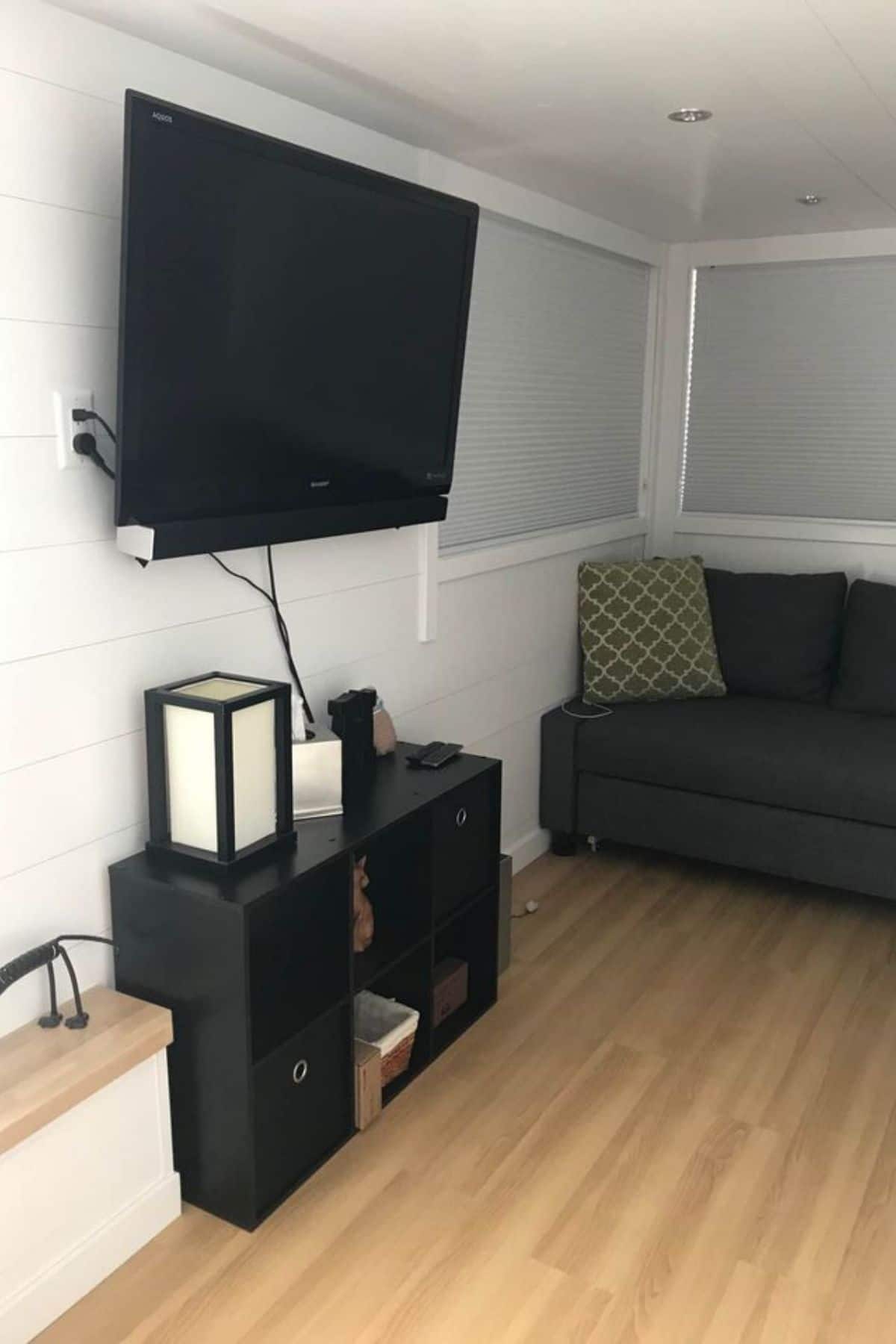 Short black shelves underneath wall mounted television on white wall