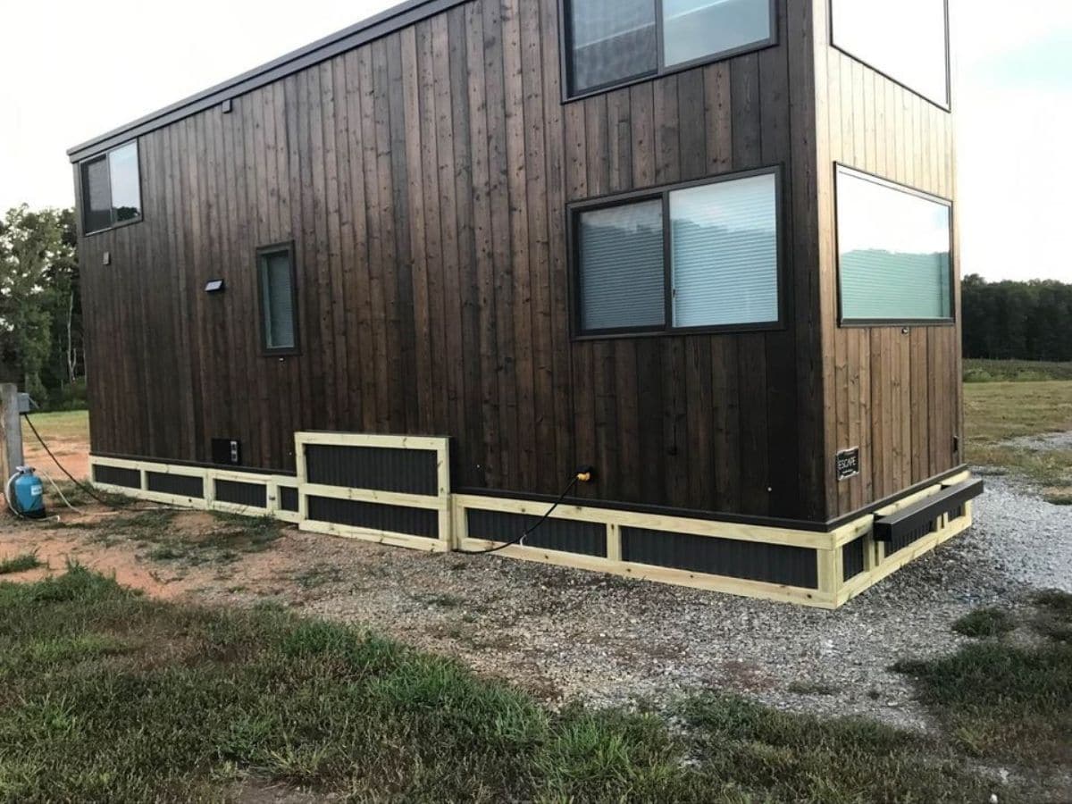 Back side of wood sided tiny home with large window on end
