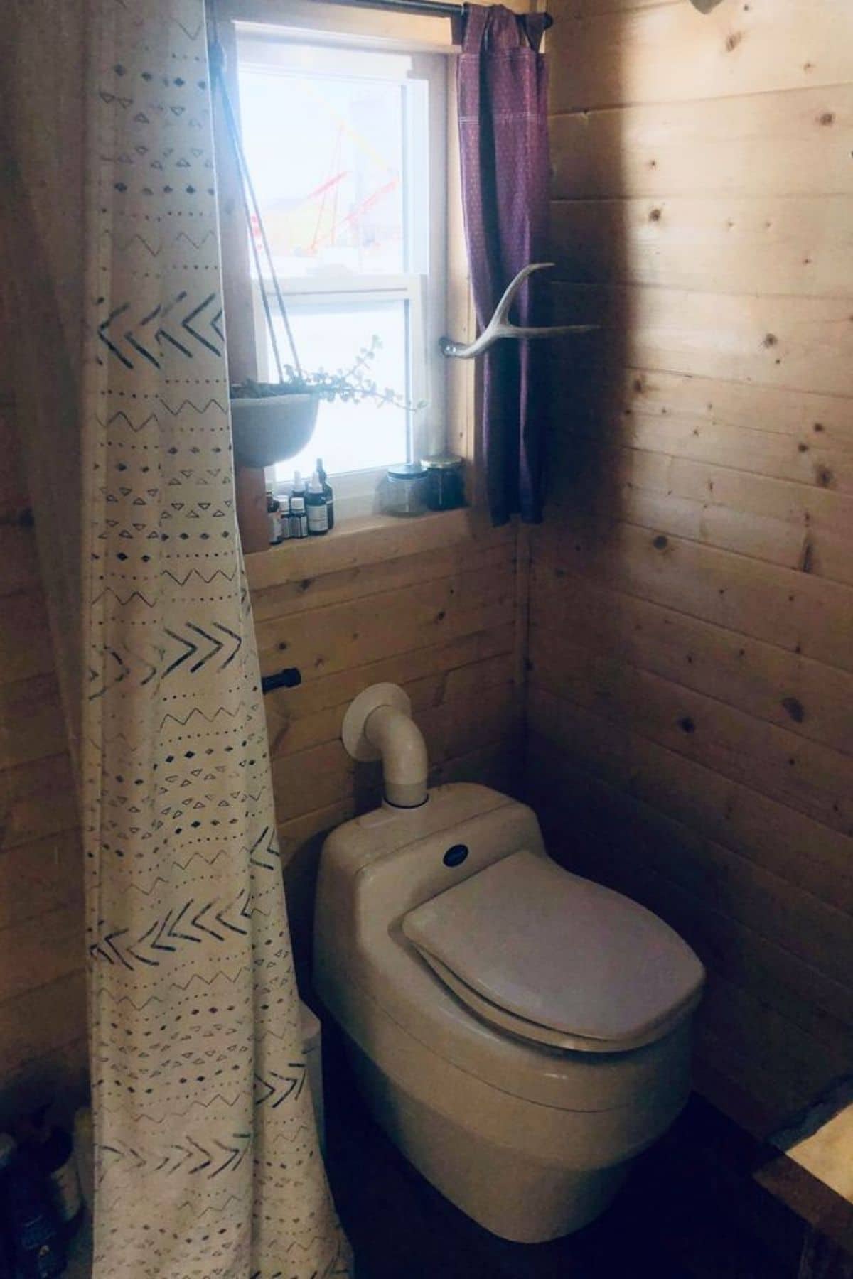 Compost toilet under window in wood bathroom