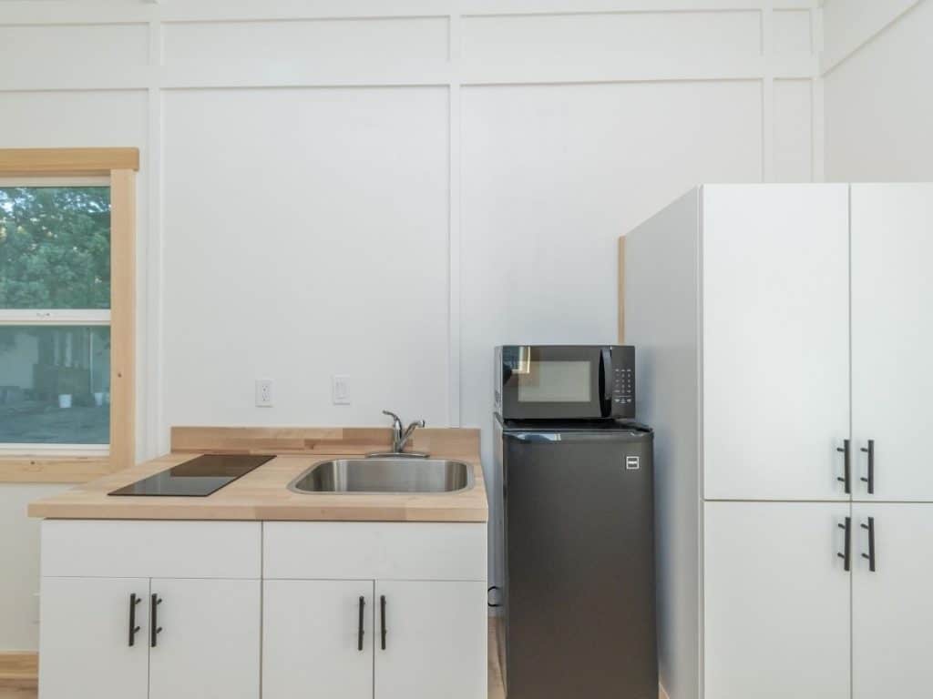 Small refrigerator next to large white cabinets