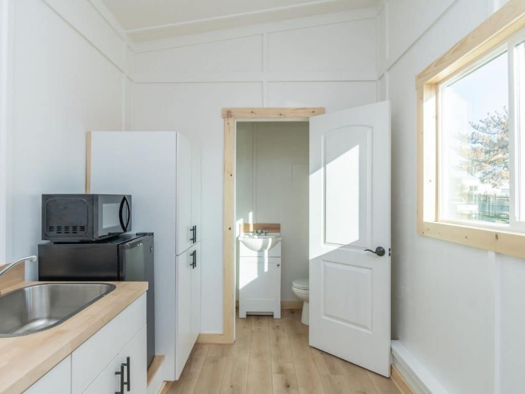 Open door into bathroom past kitchenette in tiny house