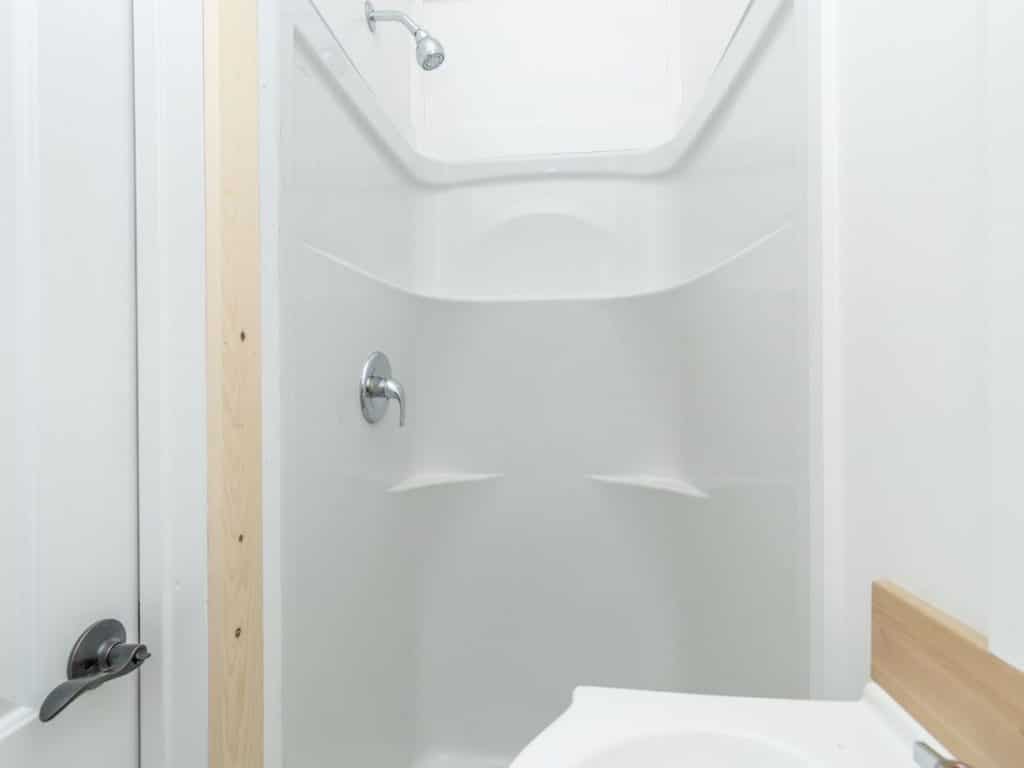 White shower stall with wood trm