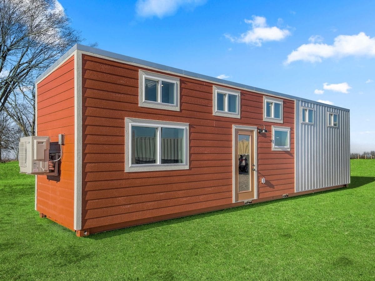 Orange container tiny home with white trim and accents on grass lot