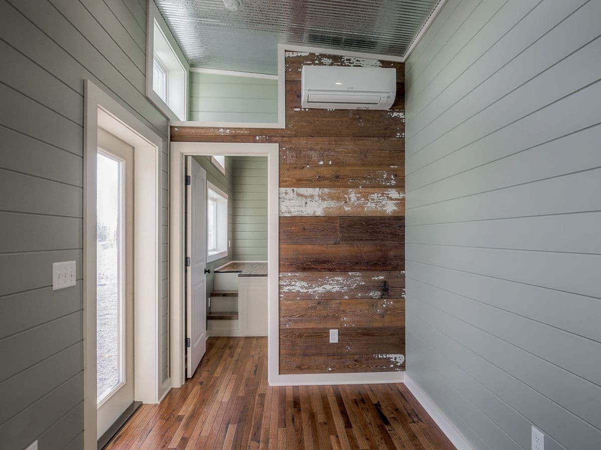 Door into bedroom next to reclaimed wood wall with mini split AC on wall