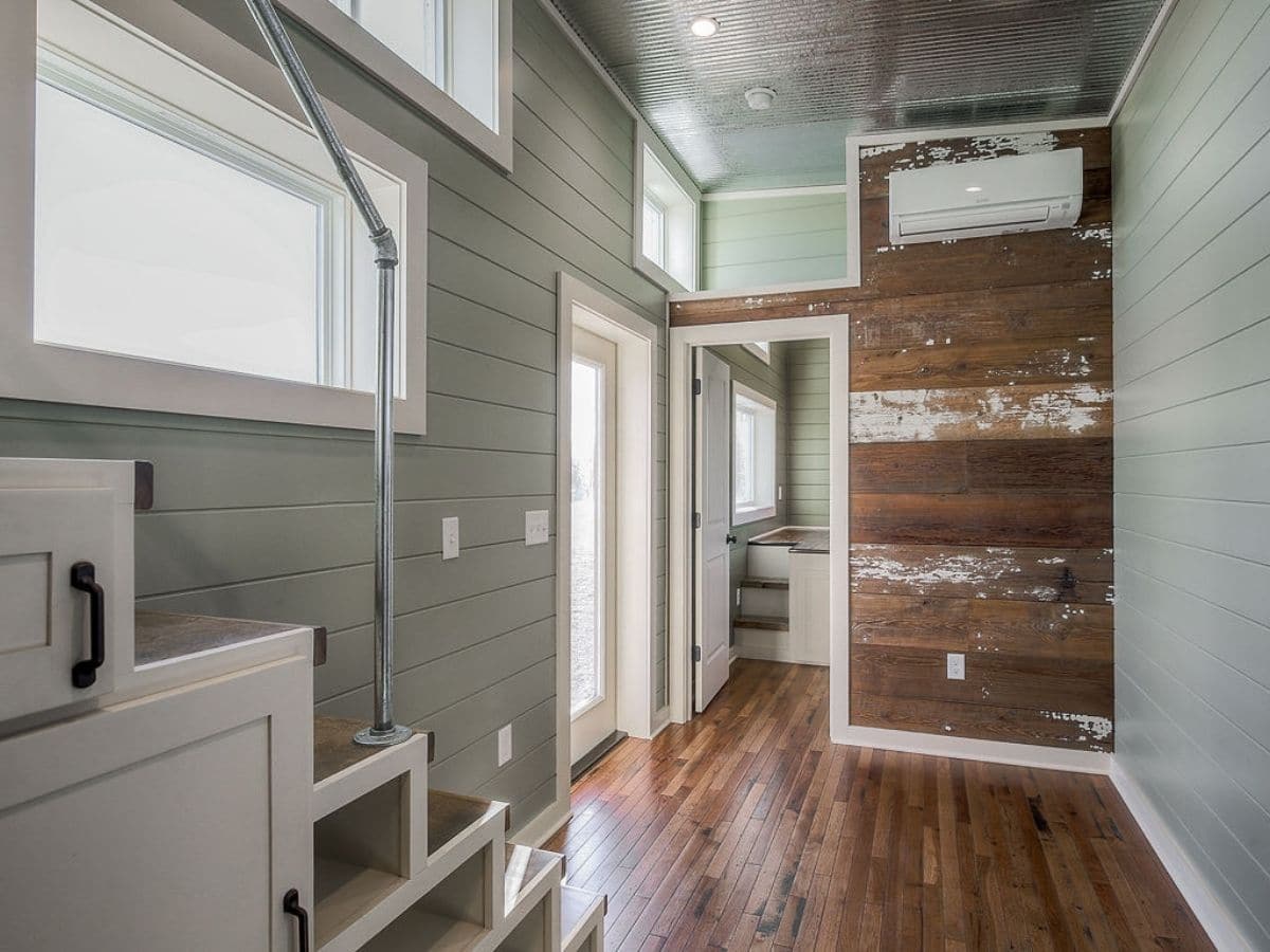 Reclaimed wood wall next to open door frame in room with white stairs in foreground