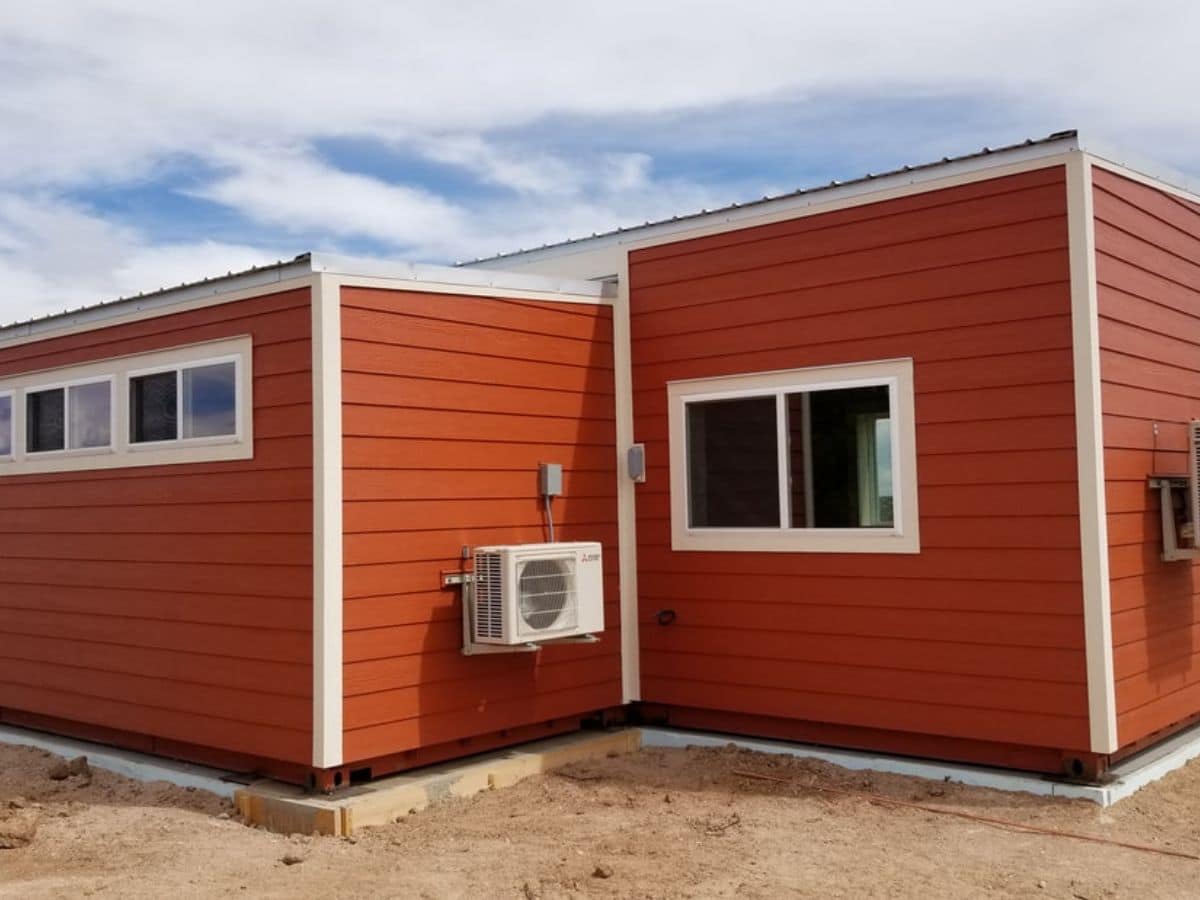 Back of orange tiny home with extra room and white trim