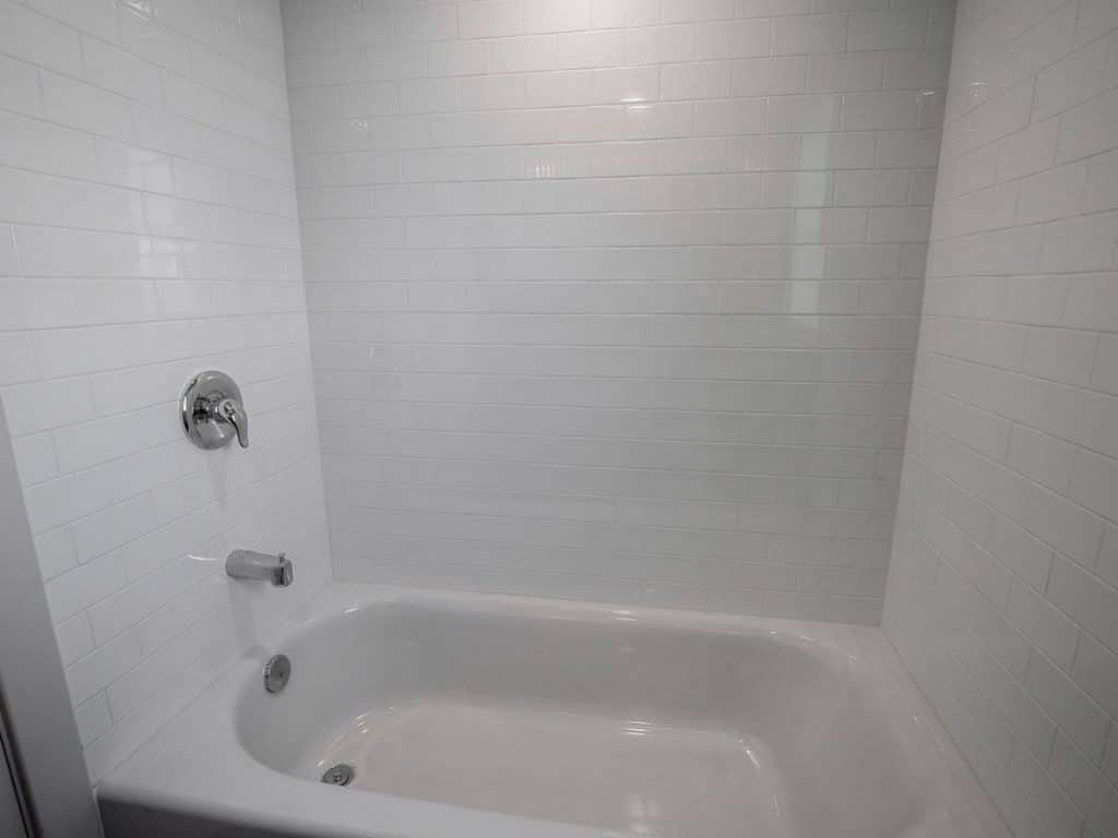White bathtub with white tile shower walls
