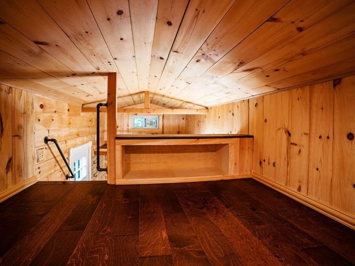 Wood floor in loft with small shelf by rail down to main floor