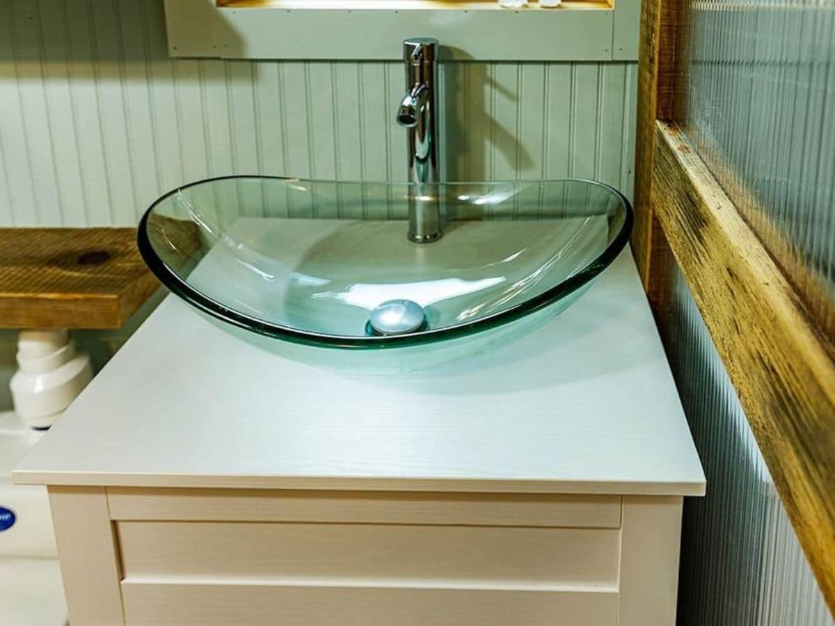 Glass bowl sink above white vanity cabinet