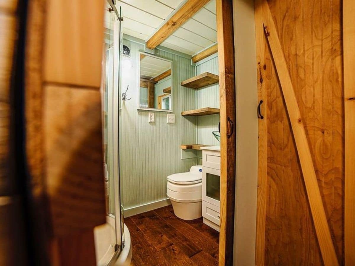 View into bathroom from door showing toilet and wooden floors