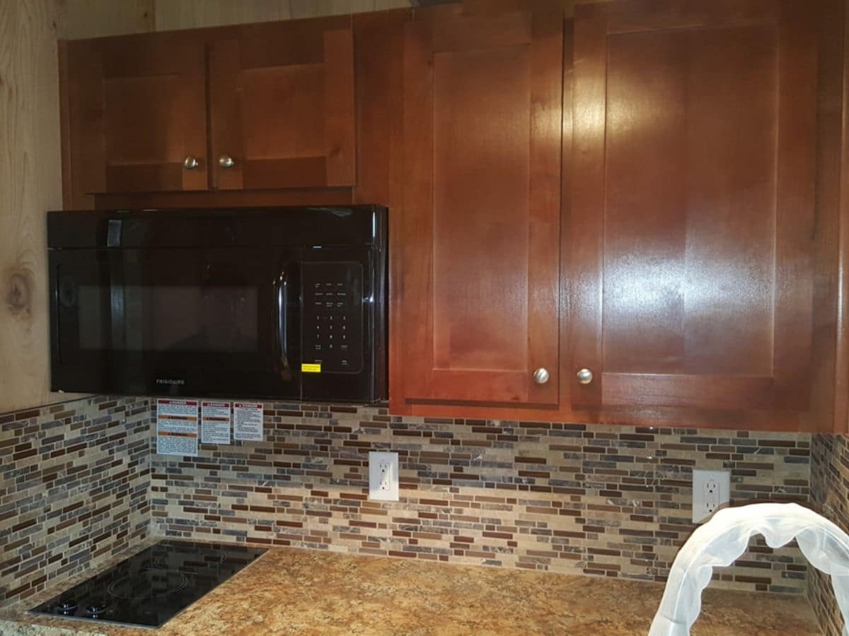 Corner of kitchen counter with tile backsplash and wood cabinet