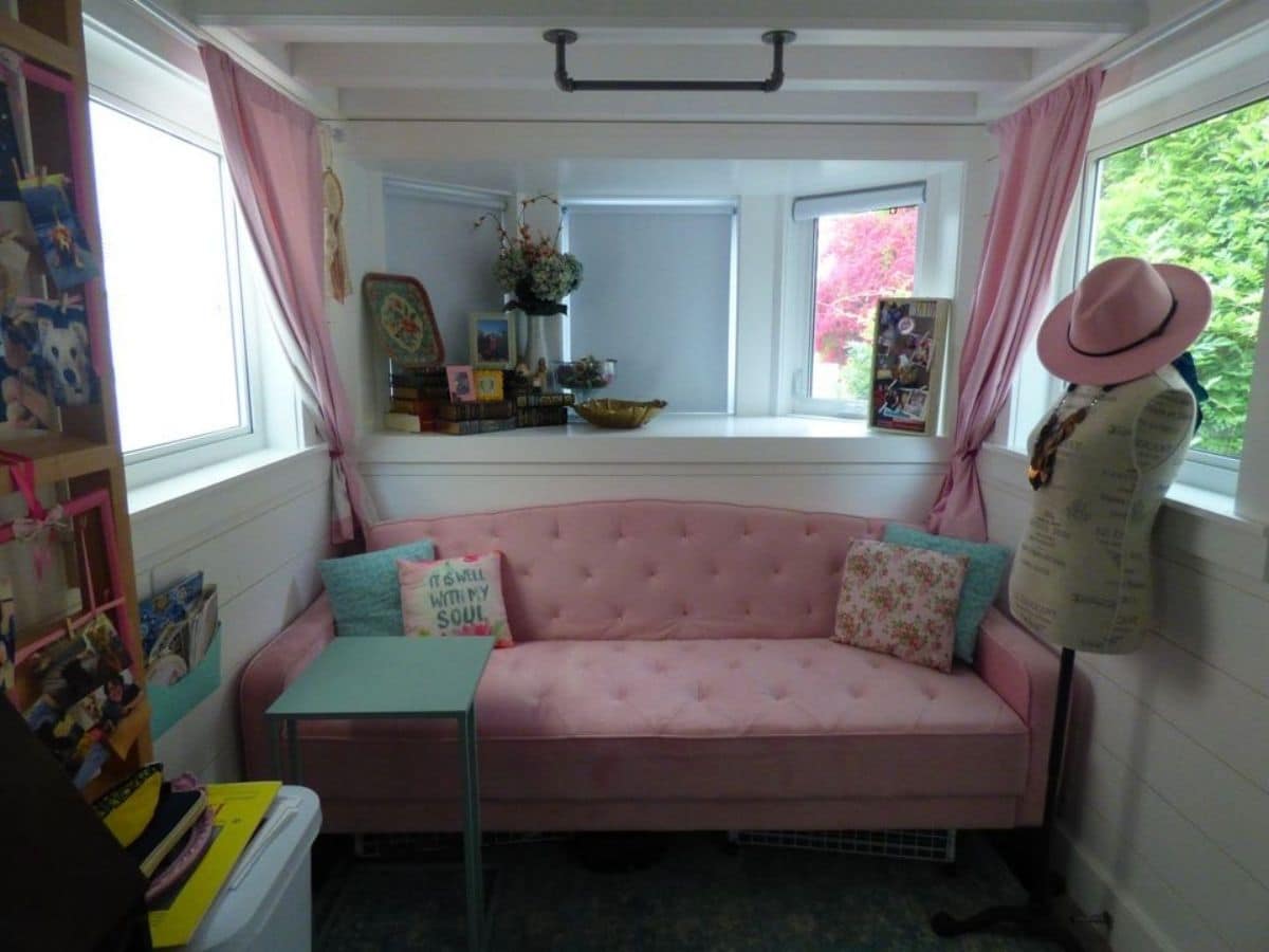 Pink sofa against wall with windows above and pink curtains
