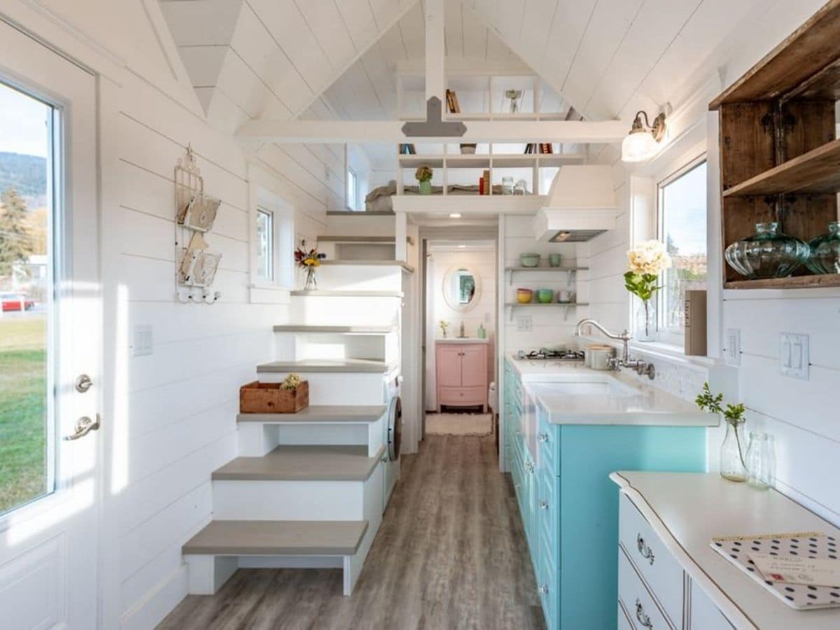 Empty kitchen with teal and white cabinets and stairs to loft