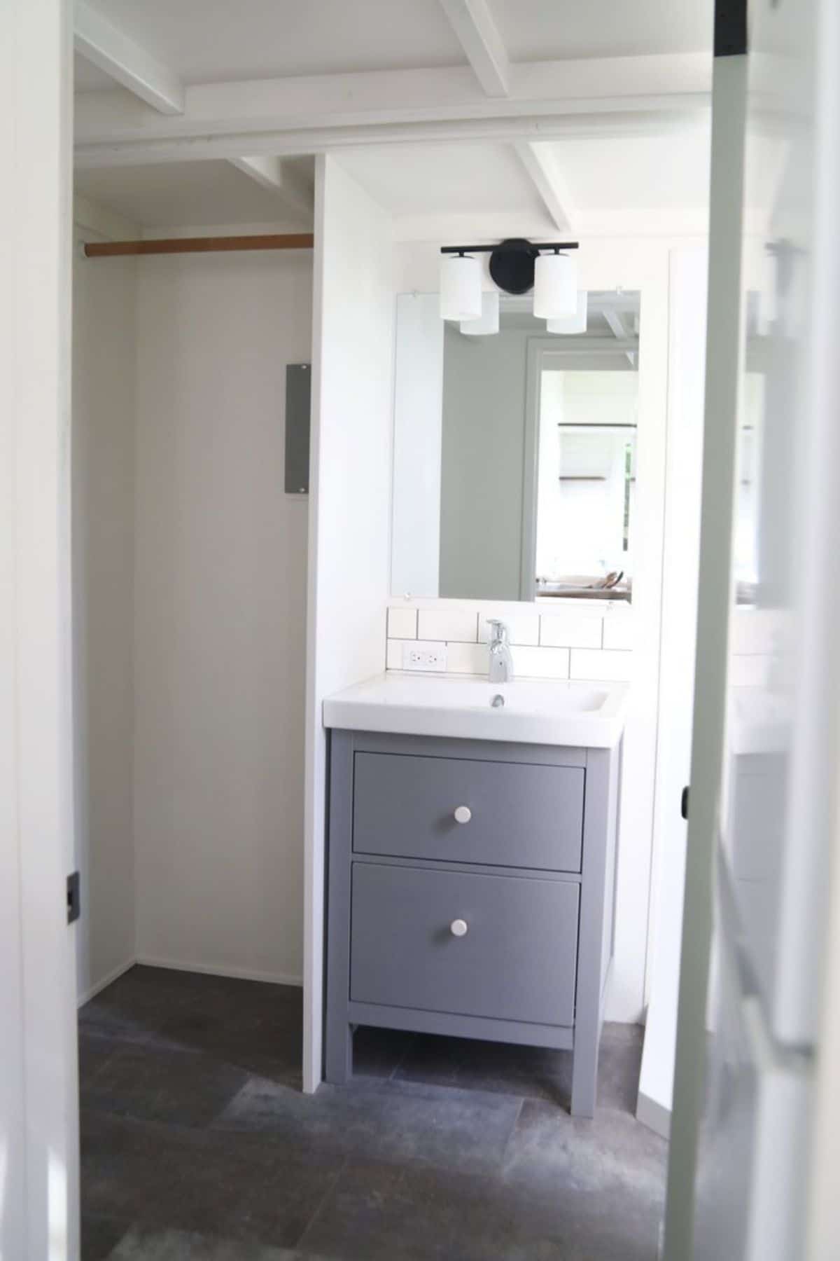 Gray vanity base in bathroom with small closet by mirror