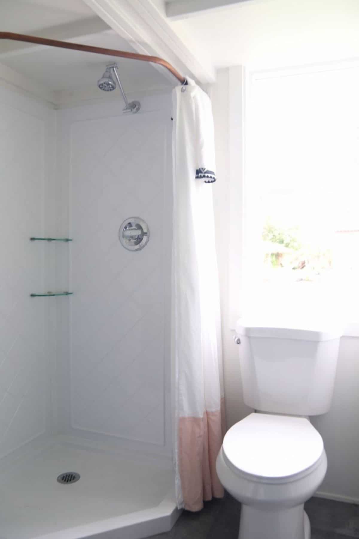 Shower stall with built in shelf in bathroom by white toilet