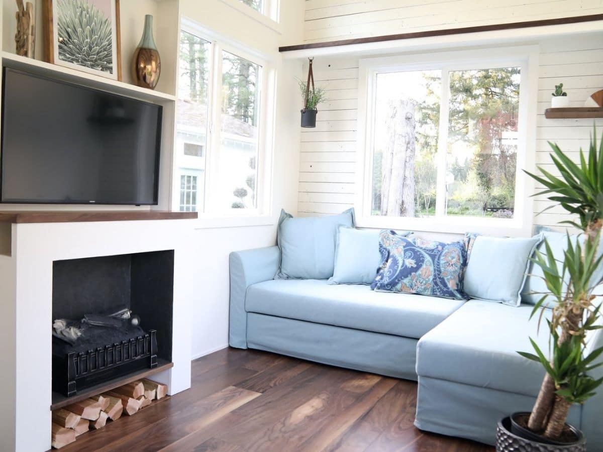 Light blue sectional sofa against windows by fireplace