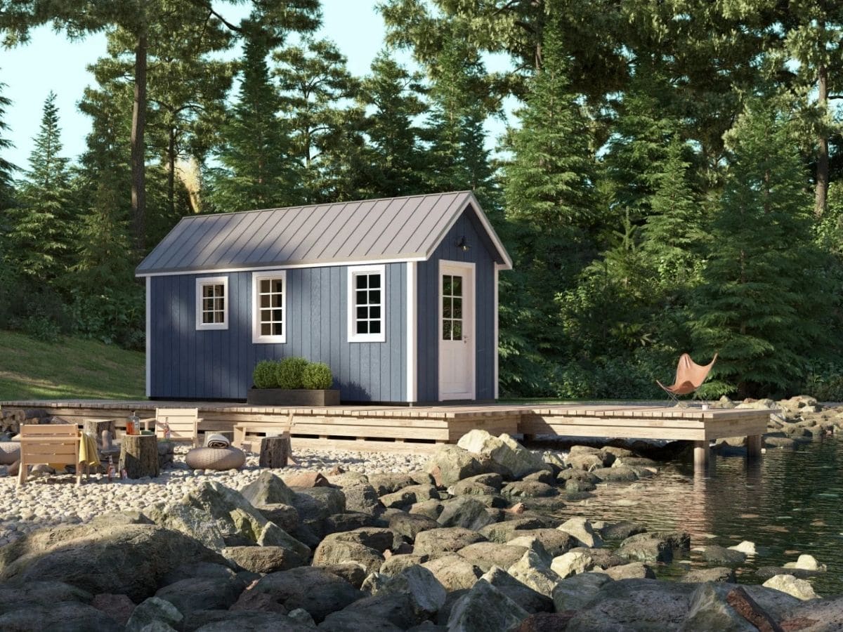 Blue tiny home with white door next to dock on pond