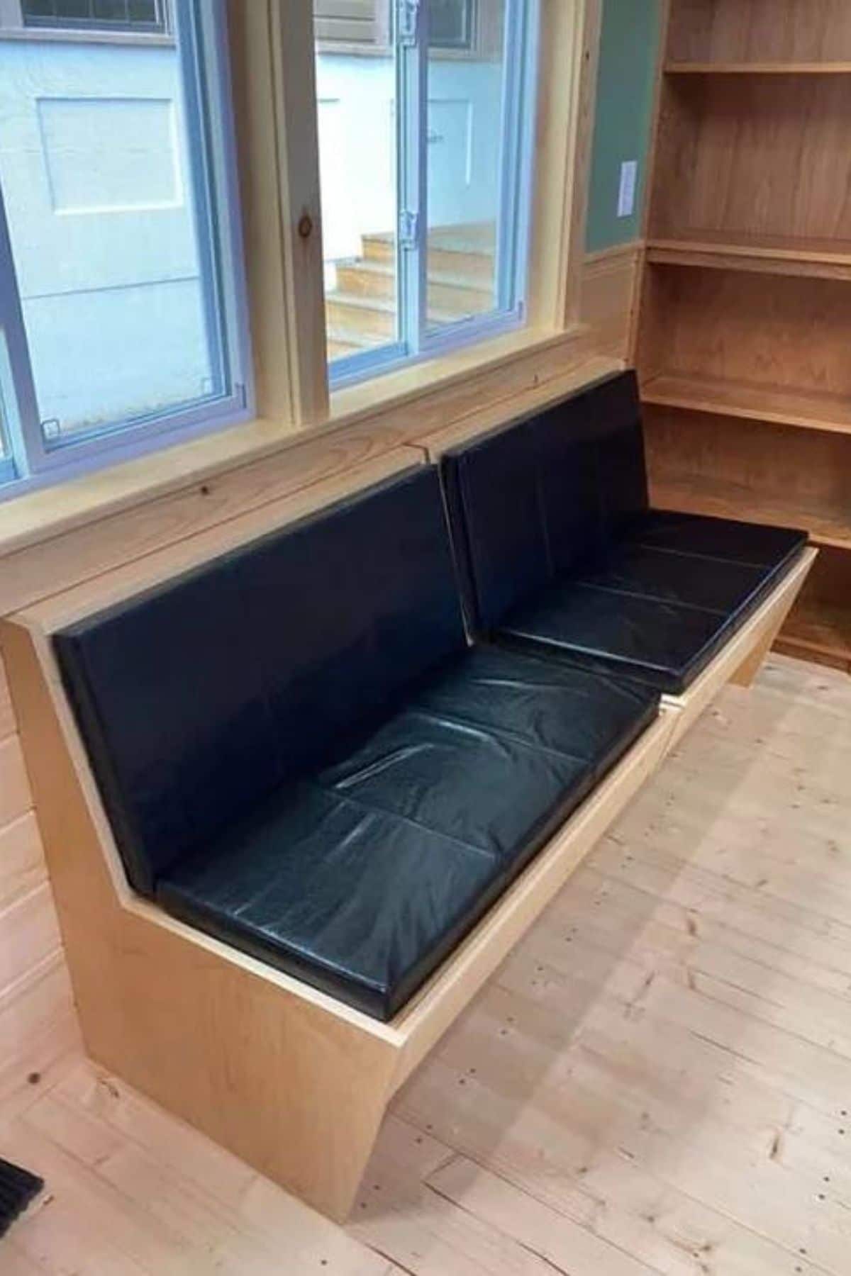 Wooden bench seat under window with black seating