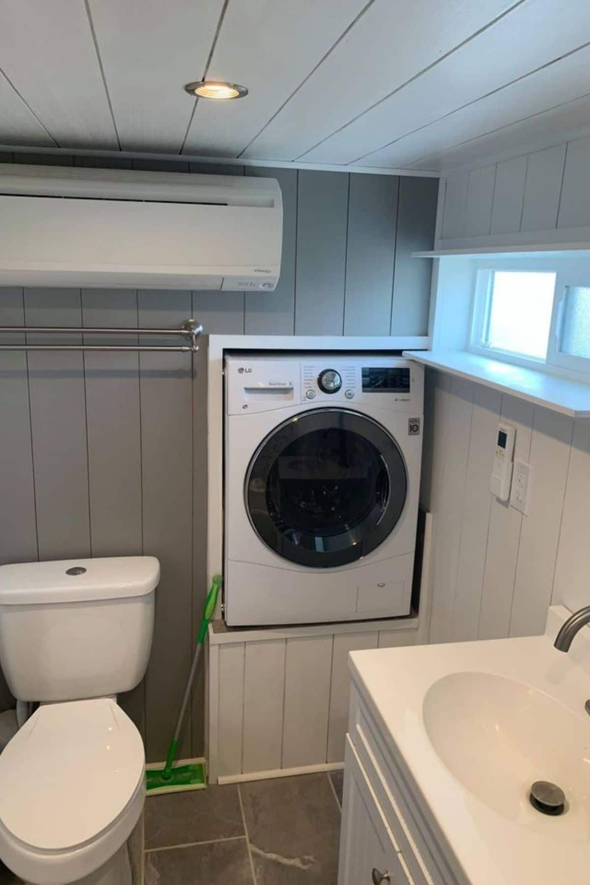 Combination washing machine mounted into white walli n bathroom with gray shiplap