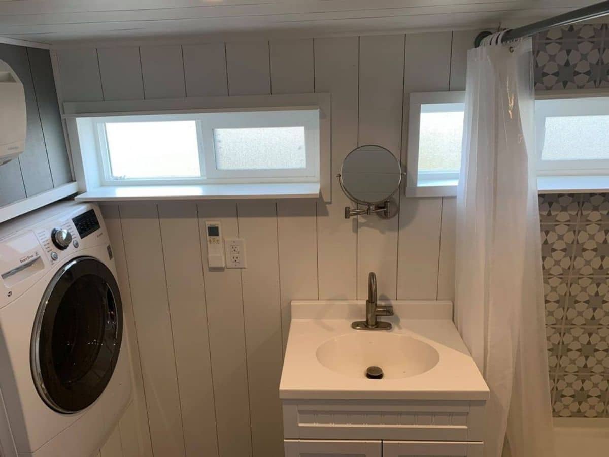 White sink with storage cabinet against wall next to shower curtain on right