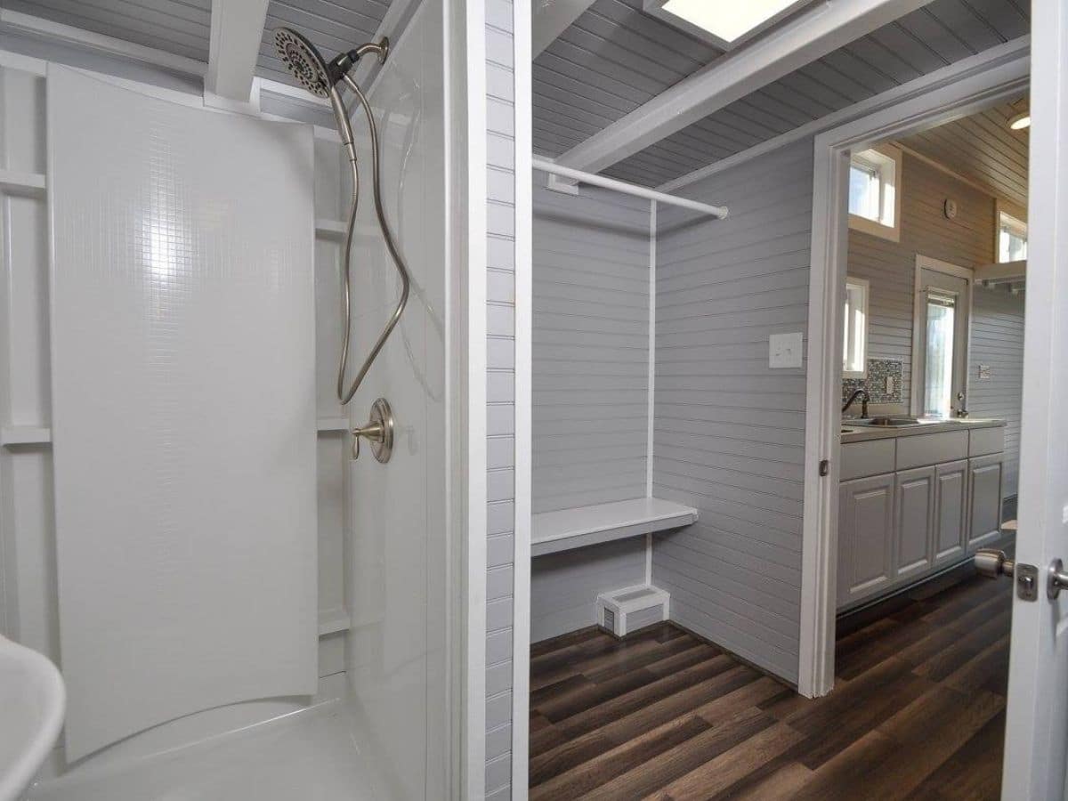 White shower stall next to open closet space with white shelves