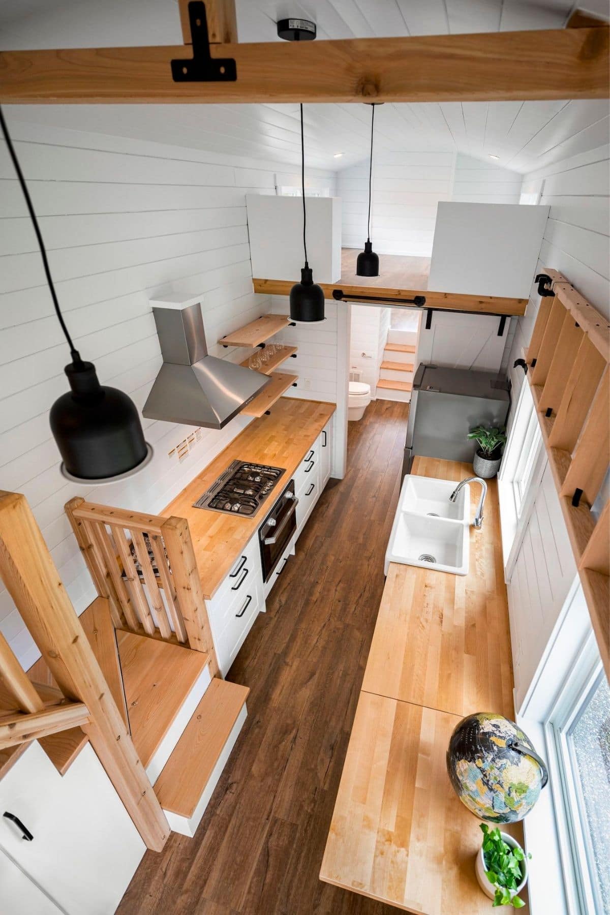 View looking down into tiny kitchen with butcherblock countertops and white cabinetry