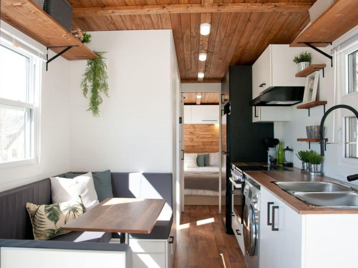 Tiny home interior with kitchen on right and dining booth on left