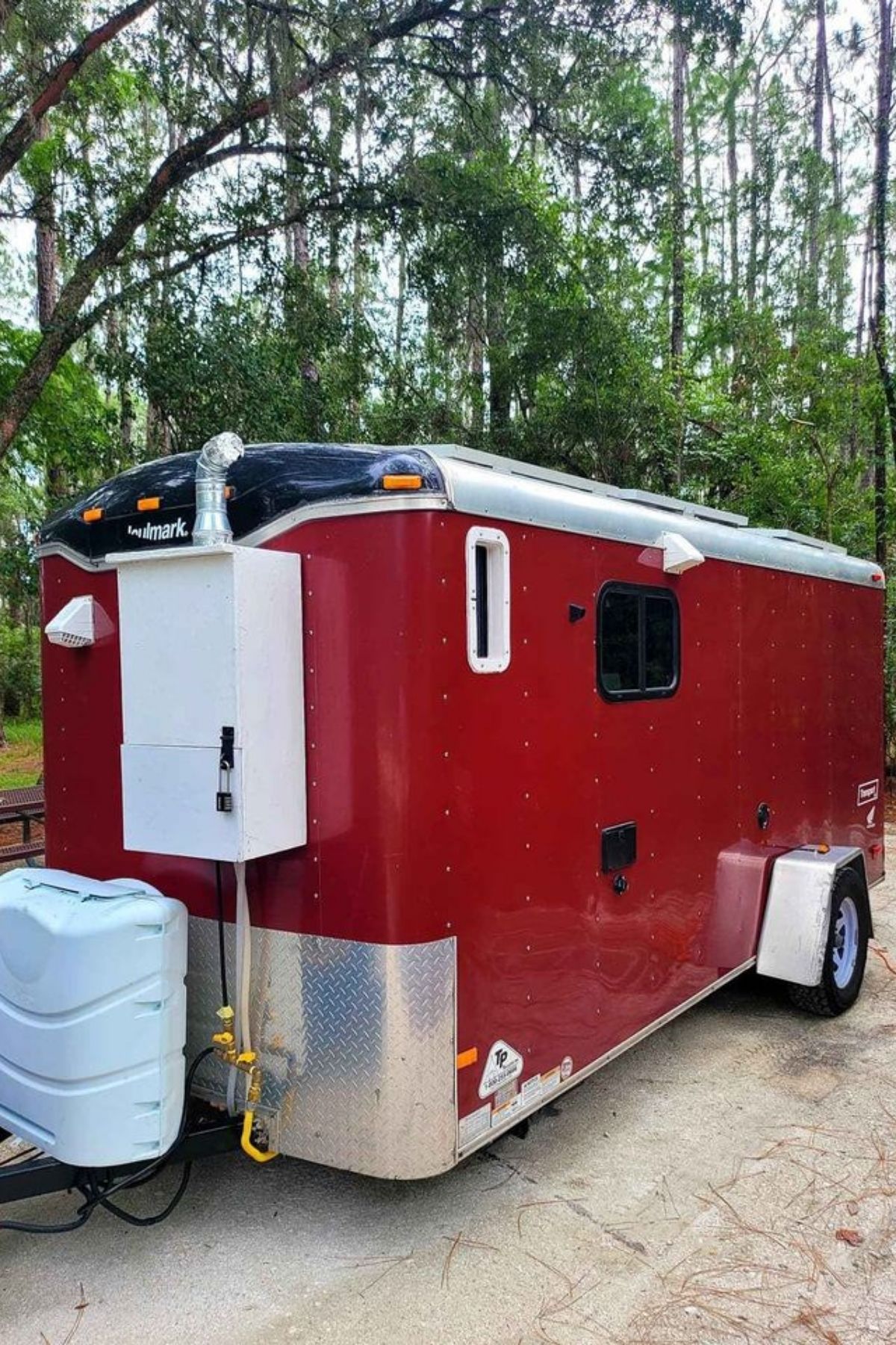 Red utility trailer tiny home with water tank on end