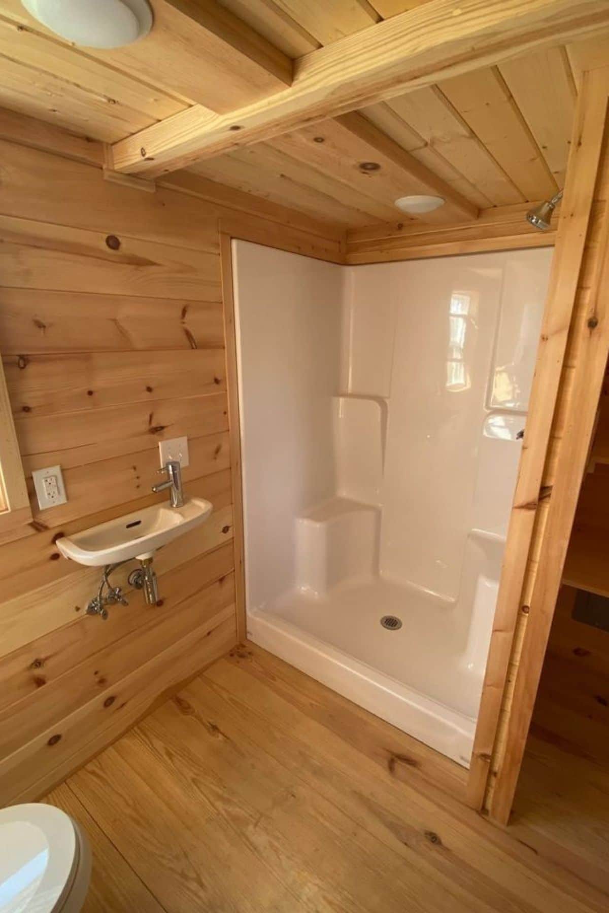 Large white shower stall against wood wall in bathroom