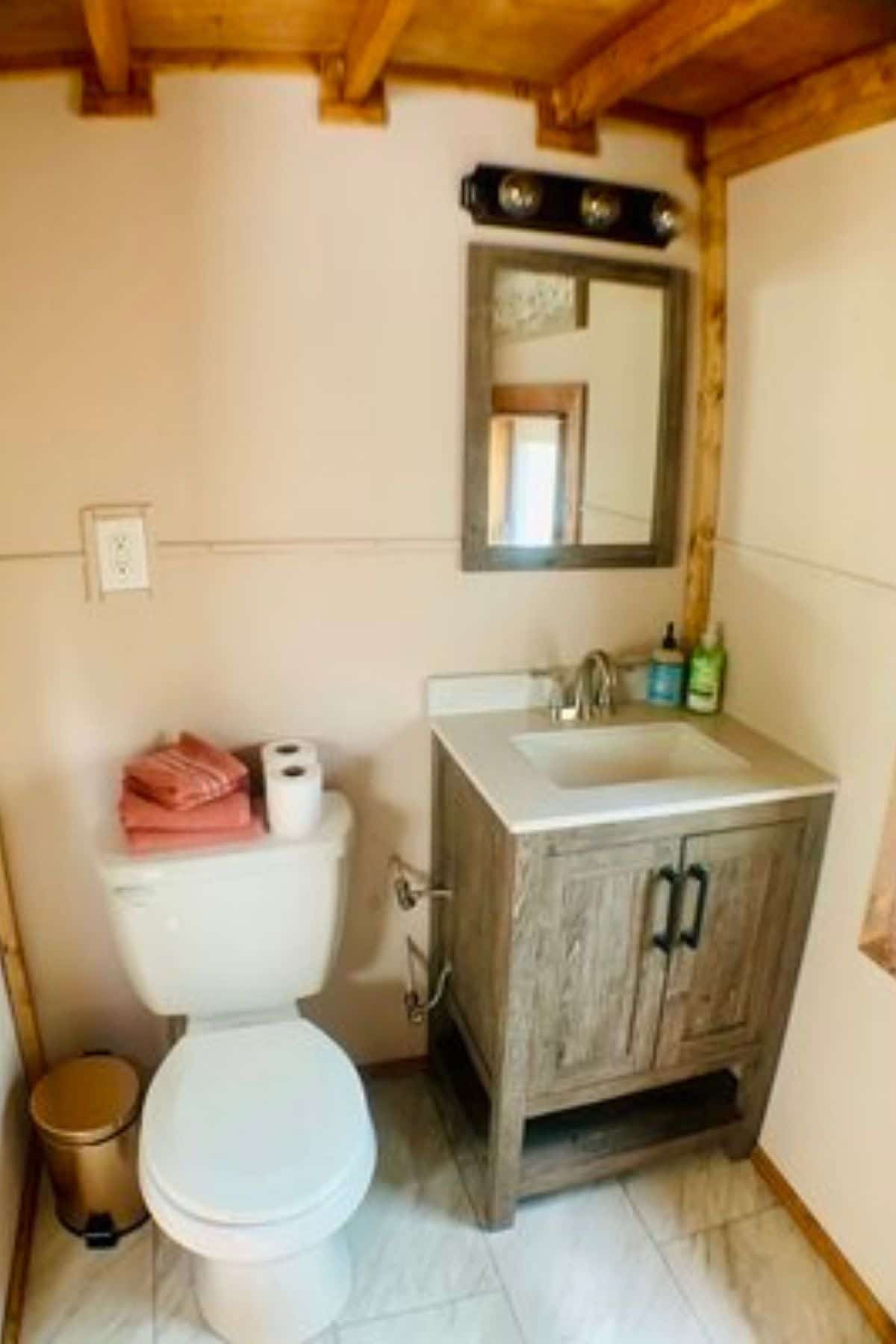 wood vanity with white sink next to white flush toilet in bathroom