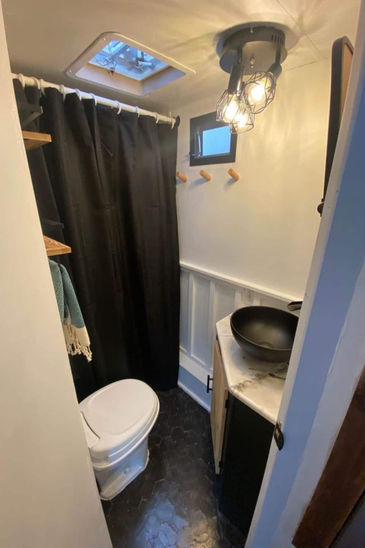 Shower with black curtain and compost toilet next to small black bowl sink