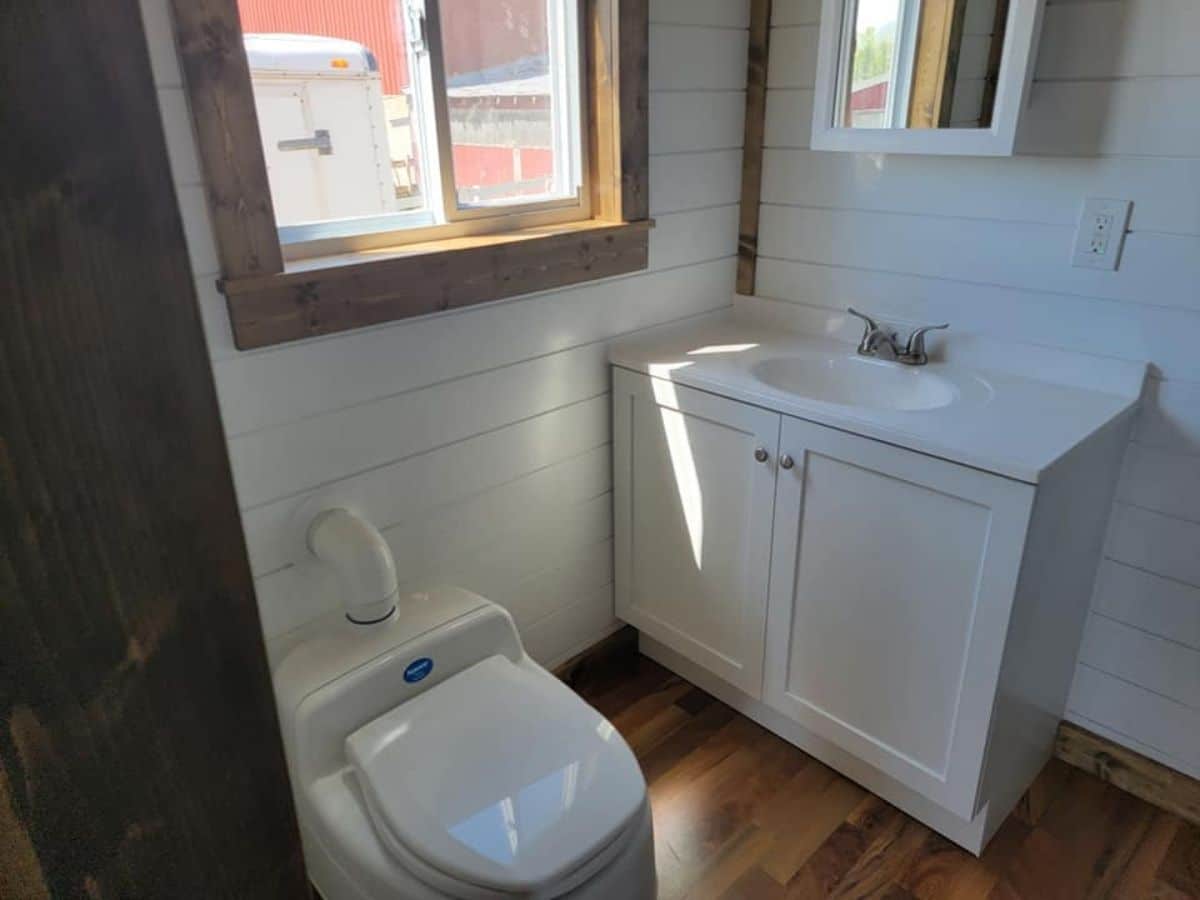 compost toilet near door with sink in background