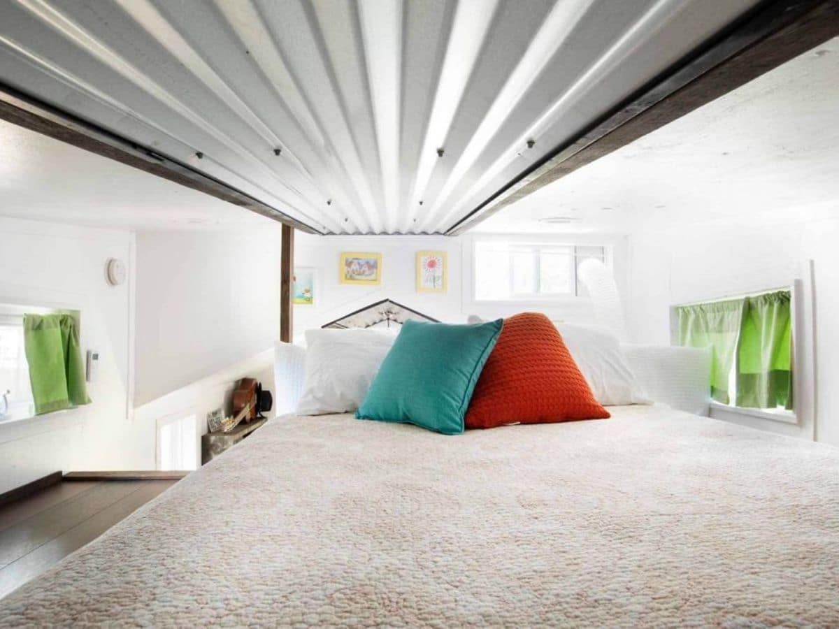 bed in loft with white bedding and colorful pillows