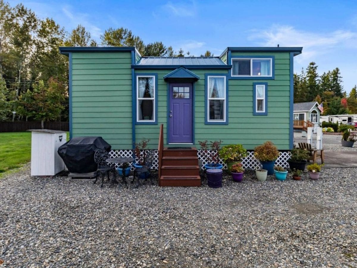 Green tiny home with blue door and two loft rafters