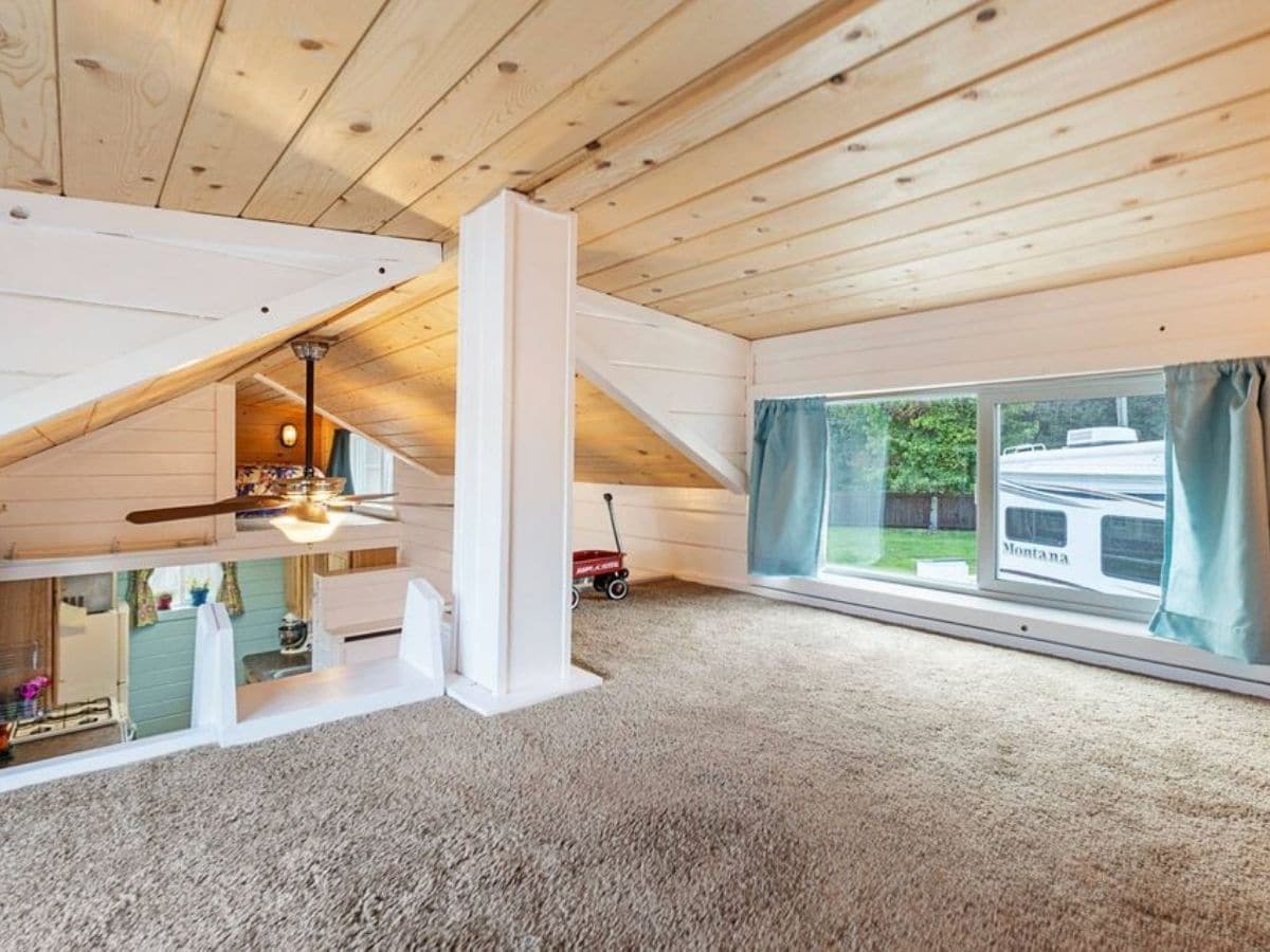 carpeted loft with window an white beams