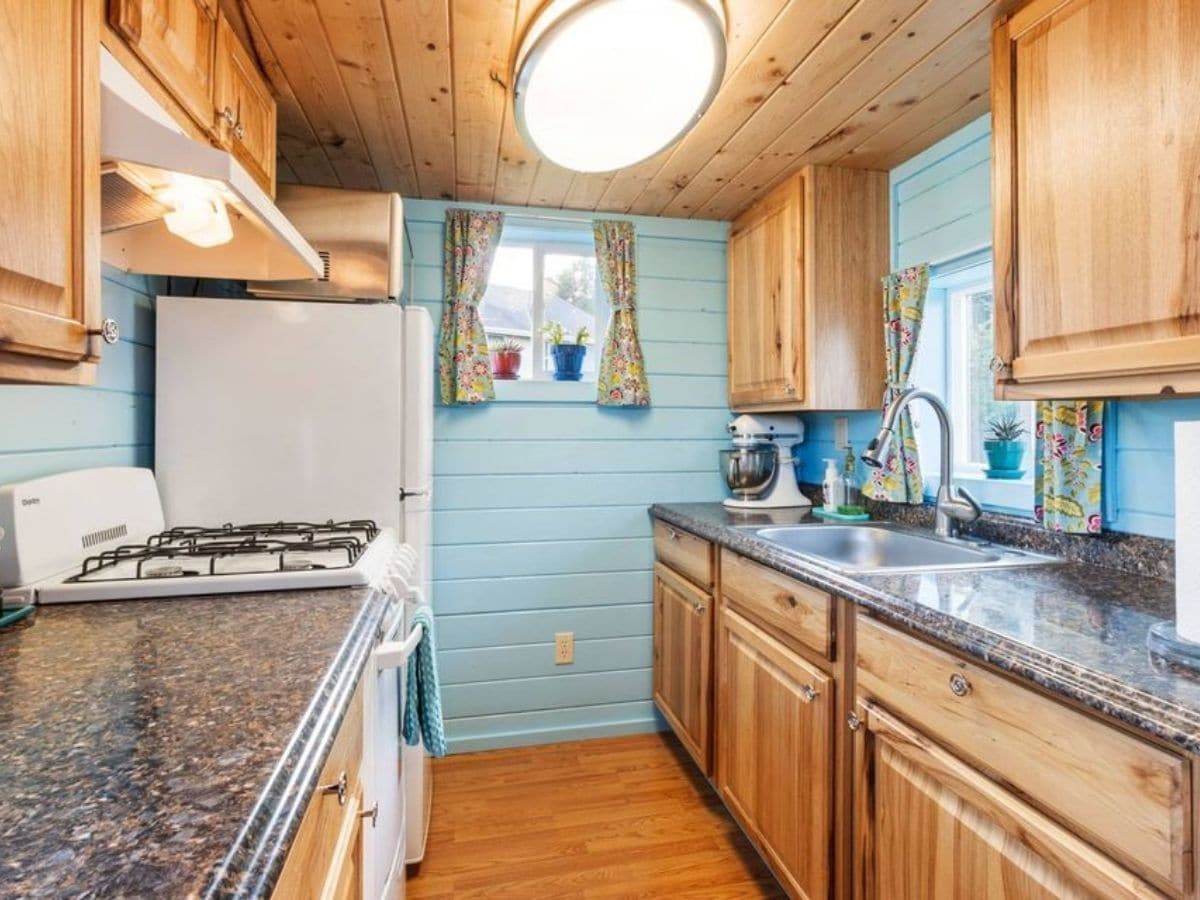 kitchen with wood cabinets and teal walls with white refrigerator on far back left of image