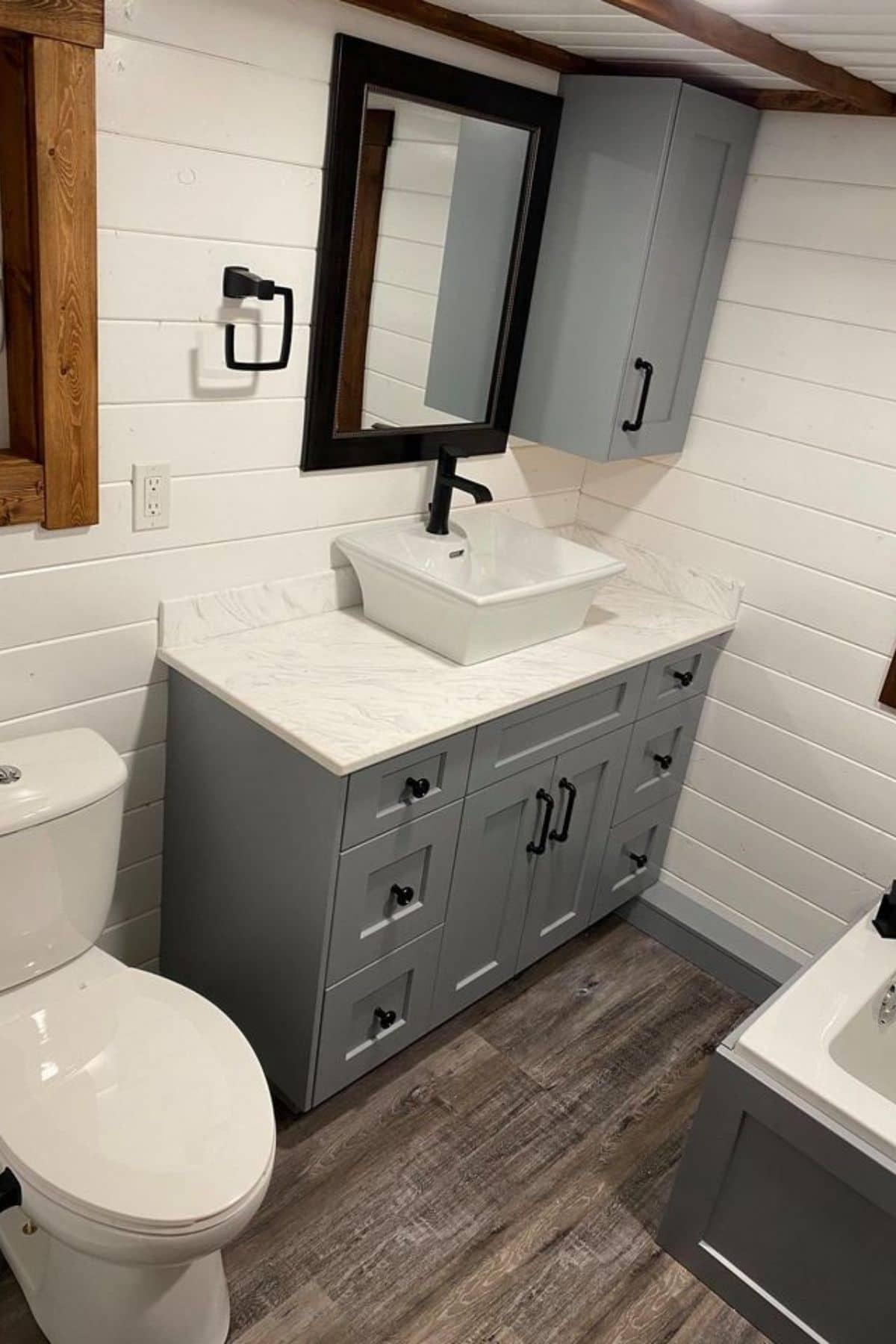 gray cabinets beneath white counter with white bowl sink next to toilet