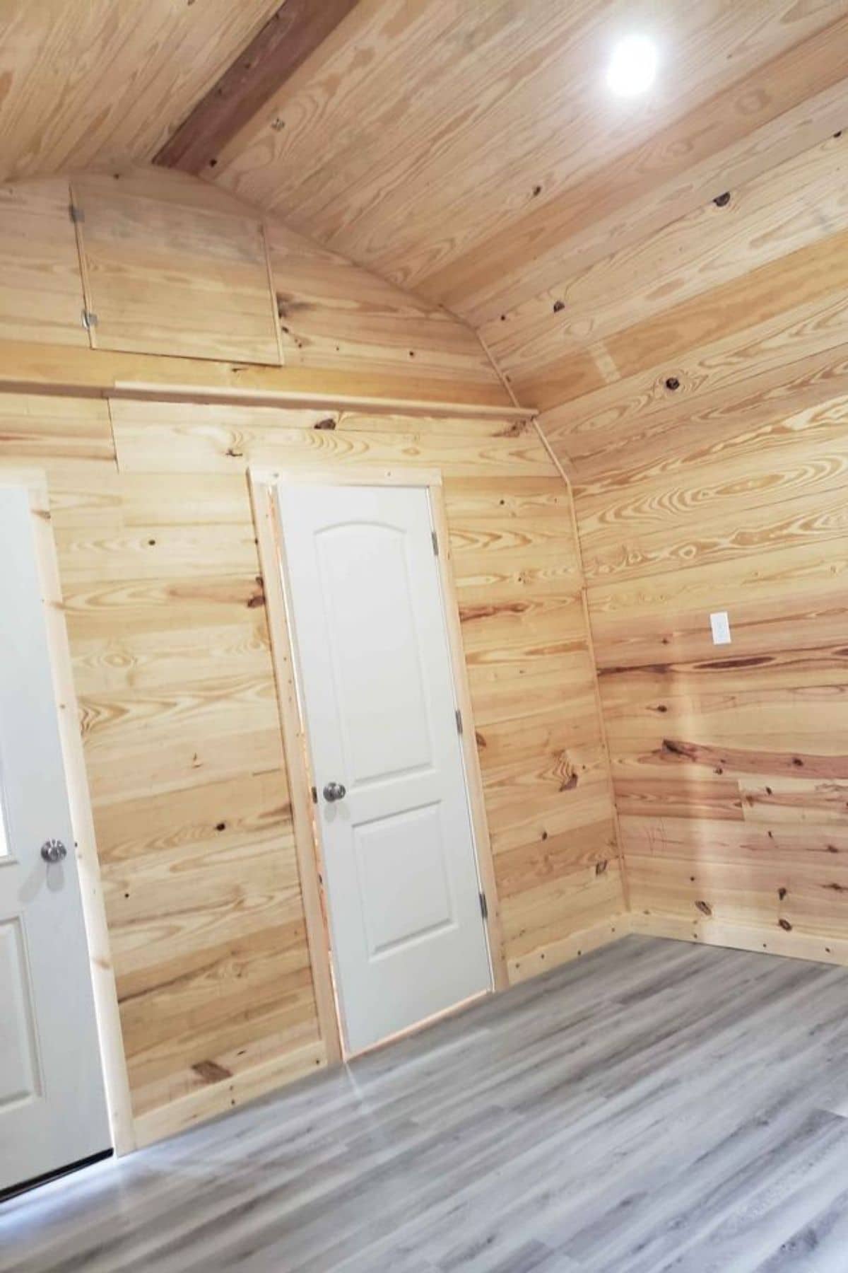 light wood walls and medium wood floor with white doors onwall