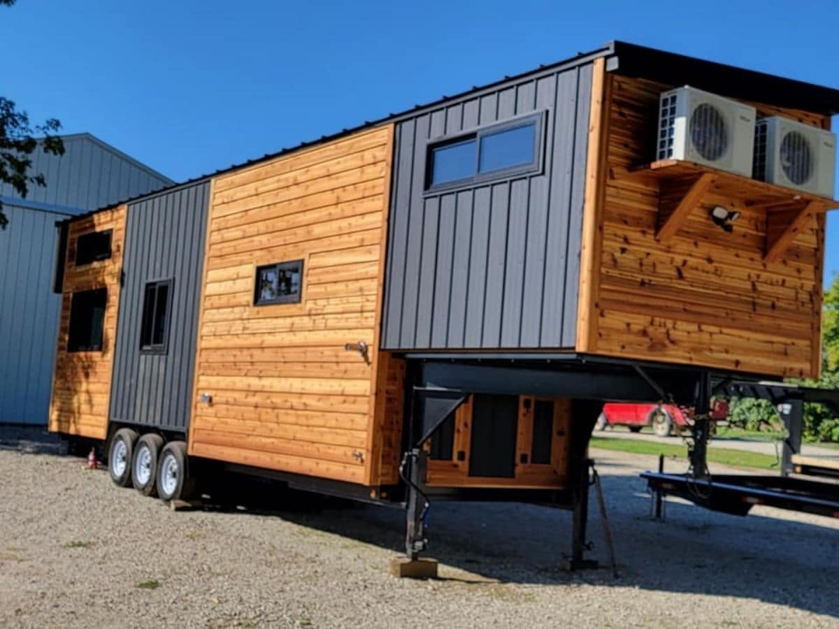side of black and wood goose neck tiny home on lot